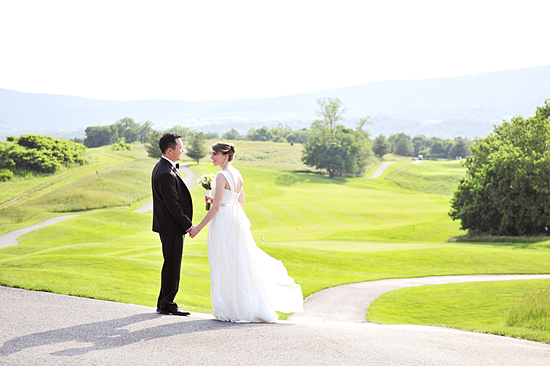 Happy couple holding hands on golf course wedding day