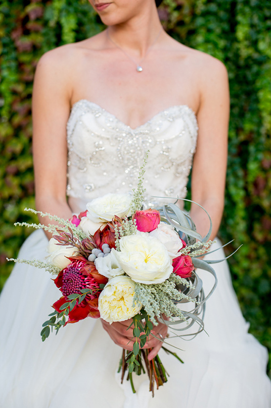 Bride holding vibrant bouquet, wearing strapless embellished wedding dress