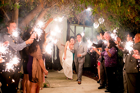 Newlyweds joyfully walk through sparklers at their wedding exit