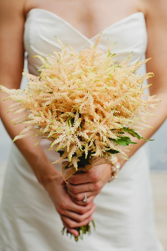 Delicate peach wedding bouquet held by bride