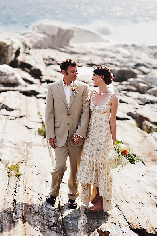 Couple in wedding attire on rocks by water