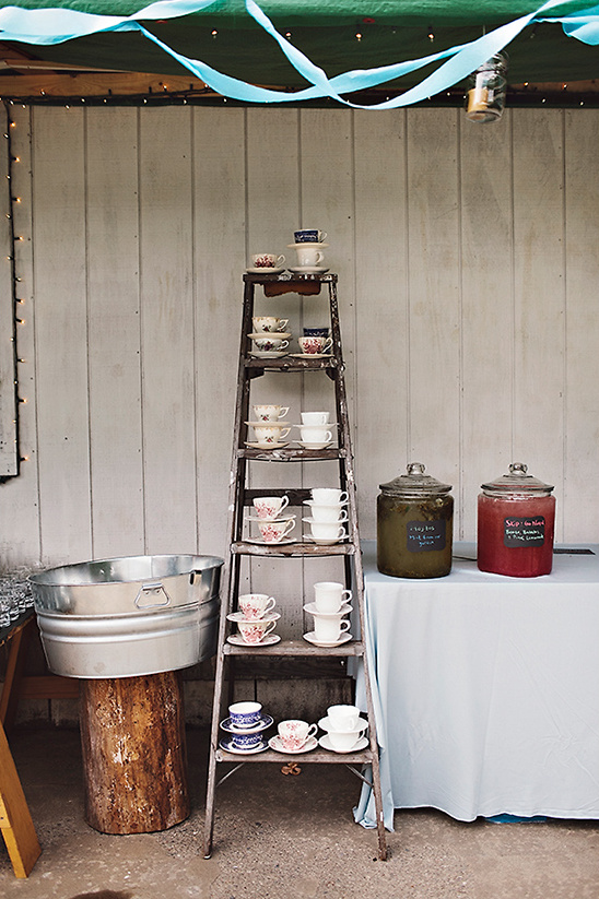 Tea cups displayed on a vintage ladder at an outdoor event
