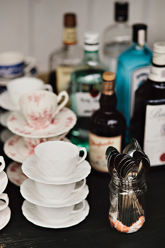 Stacked tea cups and liquor bottles on a dark surface