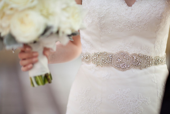 Bride holding bouquet, wearing embellished wedding belt