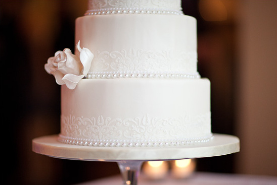 Elegant white wedding cake with pearls and lace trim