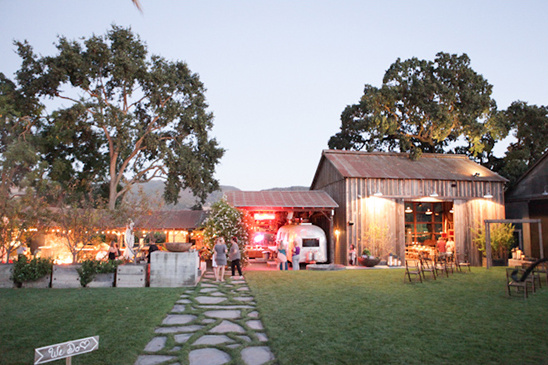 Rustic outdoor wedding venue with a pathway and vintage trailer