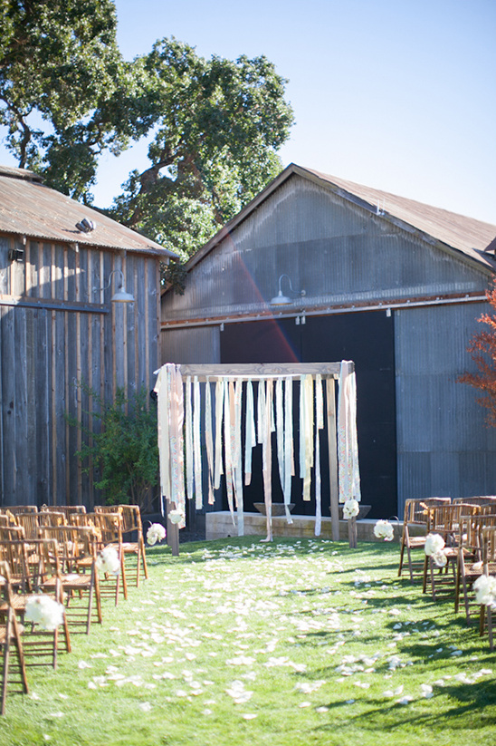 Outdoor rustic wedding ceremony setting with ribbon backdrop