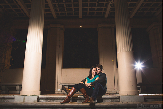 Couple embracing on steps under a stone archway, night setting