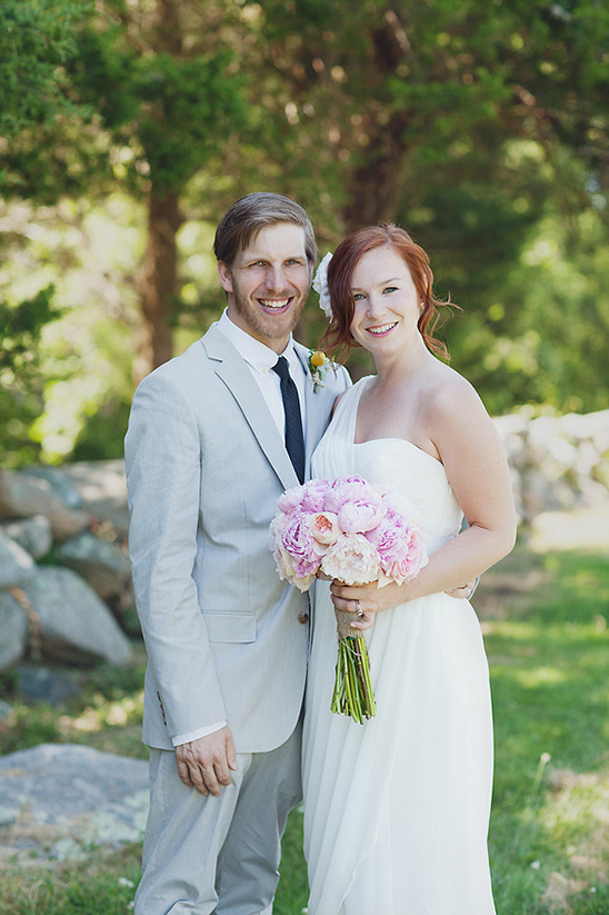Happy couple on their wedding day with pink flowers and dress