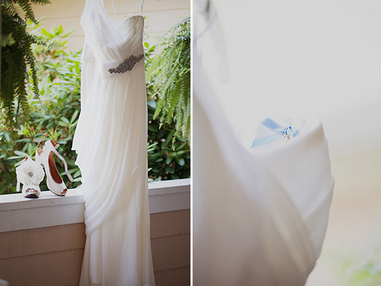 Elegant wedding dress hanging with shoes and floral bouquet