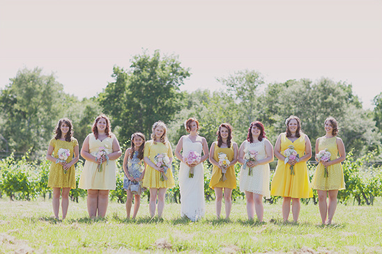 Bridesmaids in yellow dresses holding bouquets at an outdoor wedding