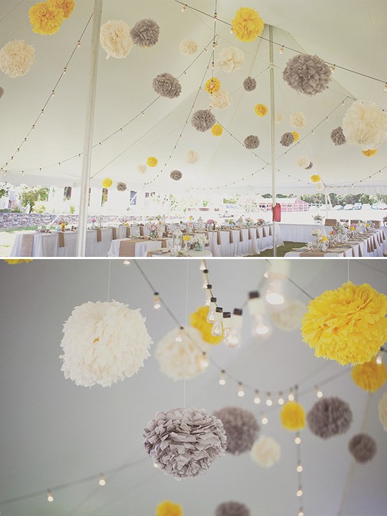 Wedding tent decorated with yellow, white, and gray pom-poms and lights