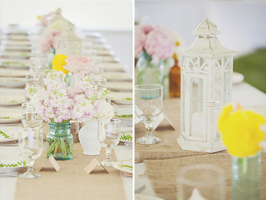 Wedding table decor with flowers and lanterns on a burlap table runner