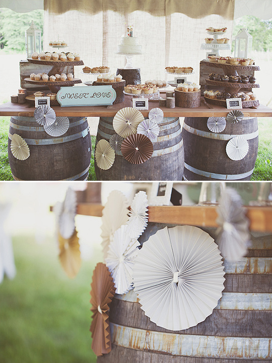 Wedding dessert table decorated with cupcakes and a cake on barrels