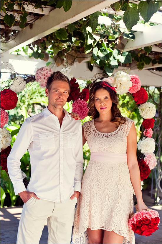 Elegant couple poses with floral arch backdrop outdoors