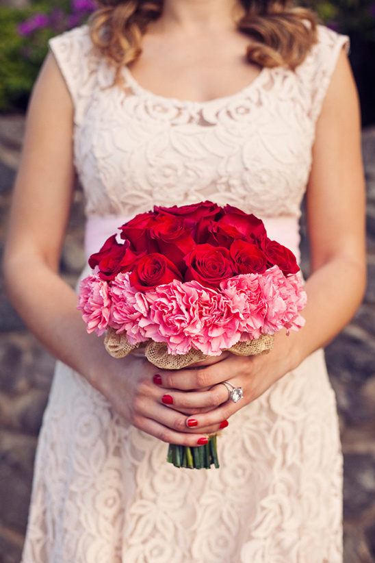 Bride holds red rose and pink carnation bouquet
