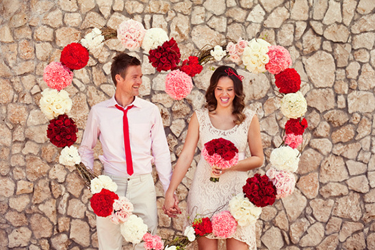 Happy couple posing with heart-shaped flower arrangement