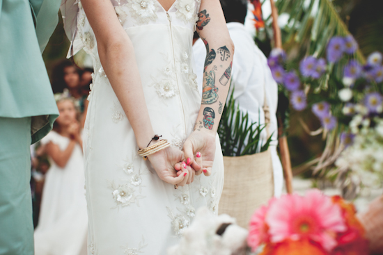 Tattooed bride in a floral wedding dress stands at alter