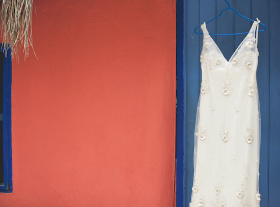 Elegant wedding dress hanging on a blue door outside