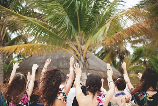Beach wedding party with hands raised in celebration
