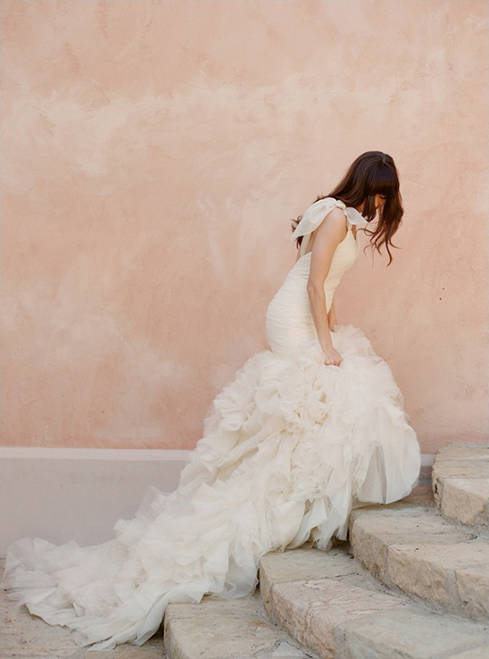 Bride in ruffled wedding gown descends stone steps