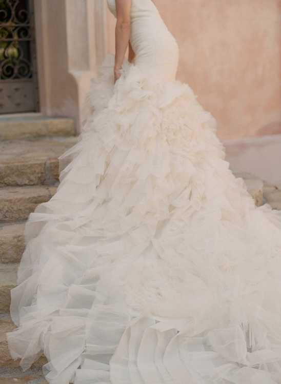 Bride in a tiered ruffled wedding gown on stone steps
