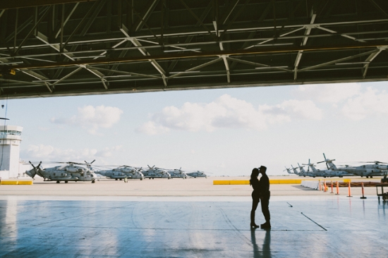 Couple embraces amid military helicopters and blue skies
