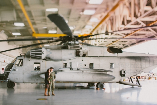 Couple poses in front of a US Marine helicopter in a hangar