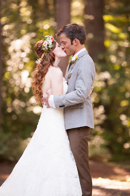 Bride and groom sharing a tender kiss in the woods
