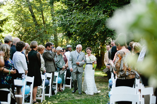 Bride walks down the aisle with her father at outdoor wedding