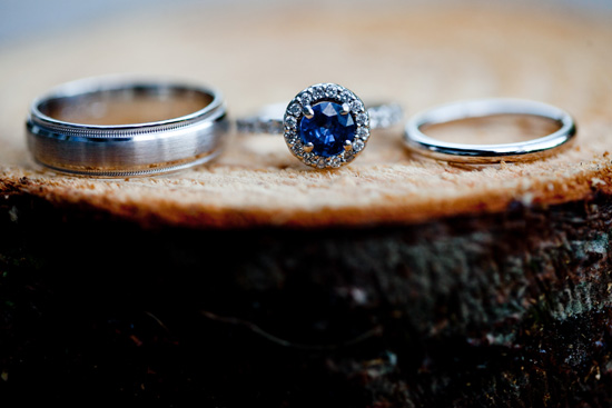 Three wedding rings on a wooden surface showcasing a sapphire ring