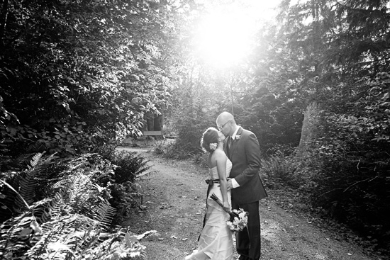 Couple kissing on their wedding day in a sunlit forest path