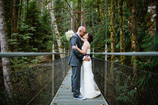 Couple shares a kiss on a forest bridge at their wedding