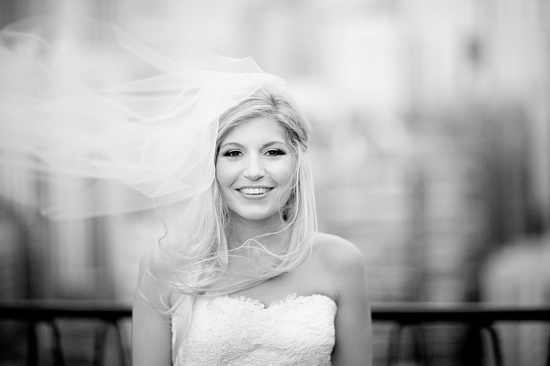 Bride smiling, veil blowing in wind, wedding day