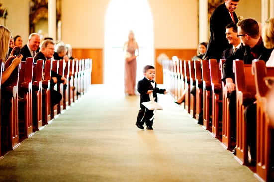 Adorable ring bearer walking down church aisle