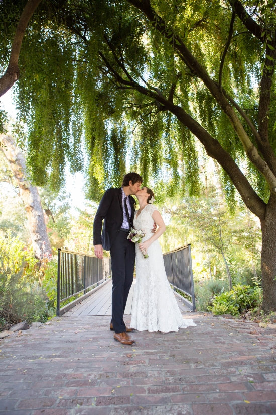 Couple kissing under trees on a bridge