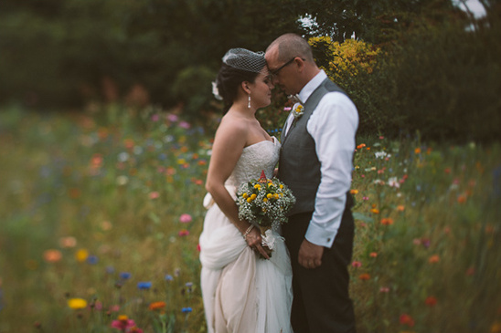 A loving couple embrace in a field of wildflowers on their wedding day