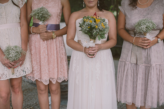 Bridesmaids in pastel lace dresses with bouquets at a wedding
