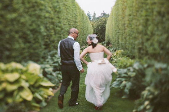 Bride and groom walk through a lush green garden path after wedding