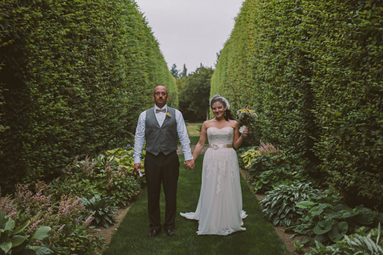 Wedding couple holding hands in a garden with hedge walls