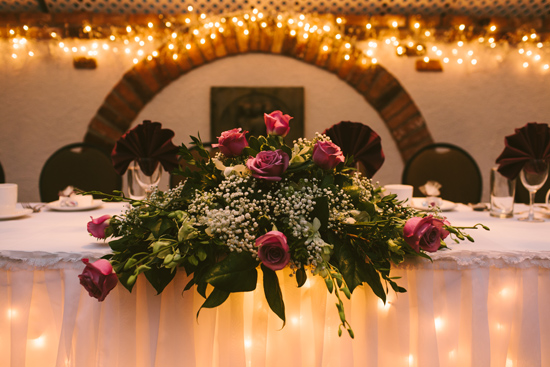 Wedding reception table decorated with flowers and warm lights