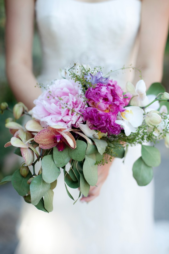 Bride holding a vibrant pink and purple flower bouquet on her wedding day
