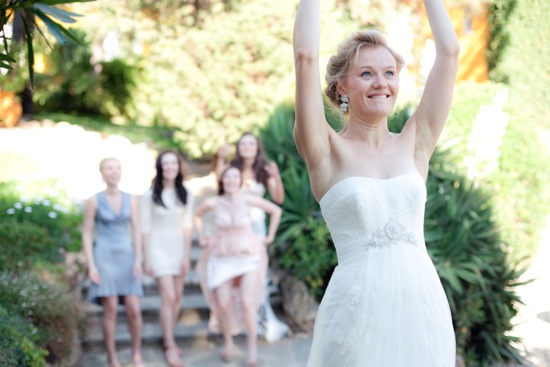 Bride throwing bouquet at wedding with excited bridesmaids