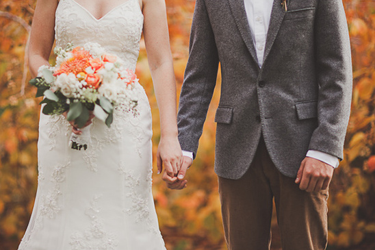 Bride and groom holding hands on their wedding day with flowers