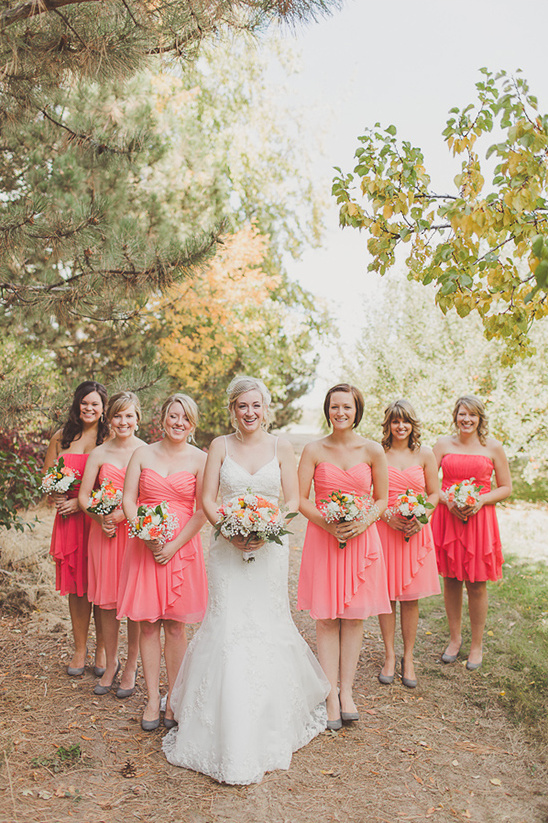 Bride with bridesmaids in coral dresses pose for wedding photos