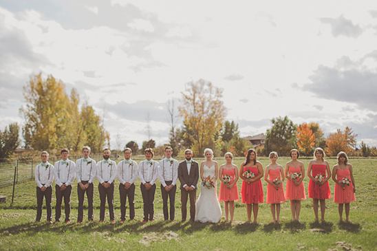 Wedding party posing for a photo in an open field under a cloudy sky