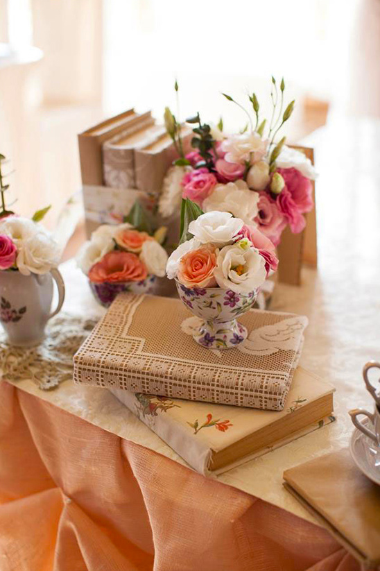 Pretty pink flowers in cup atop books