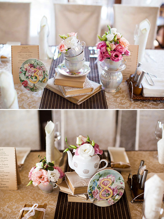 Floral centerpiece with teacups on stacked books, table number eight