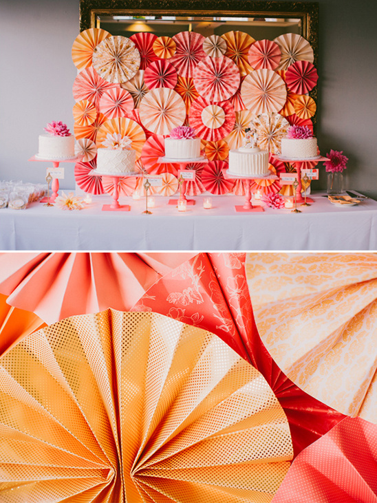 Wedding cakes on display with paper fans backdrop decoration