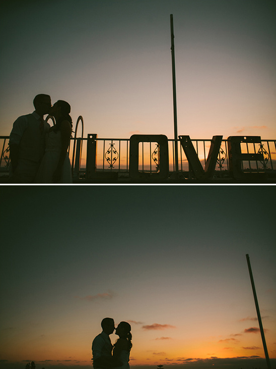 Couple kissing at sunset with LOVE sign silhouette